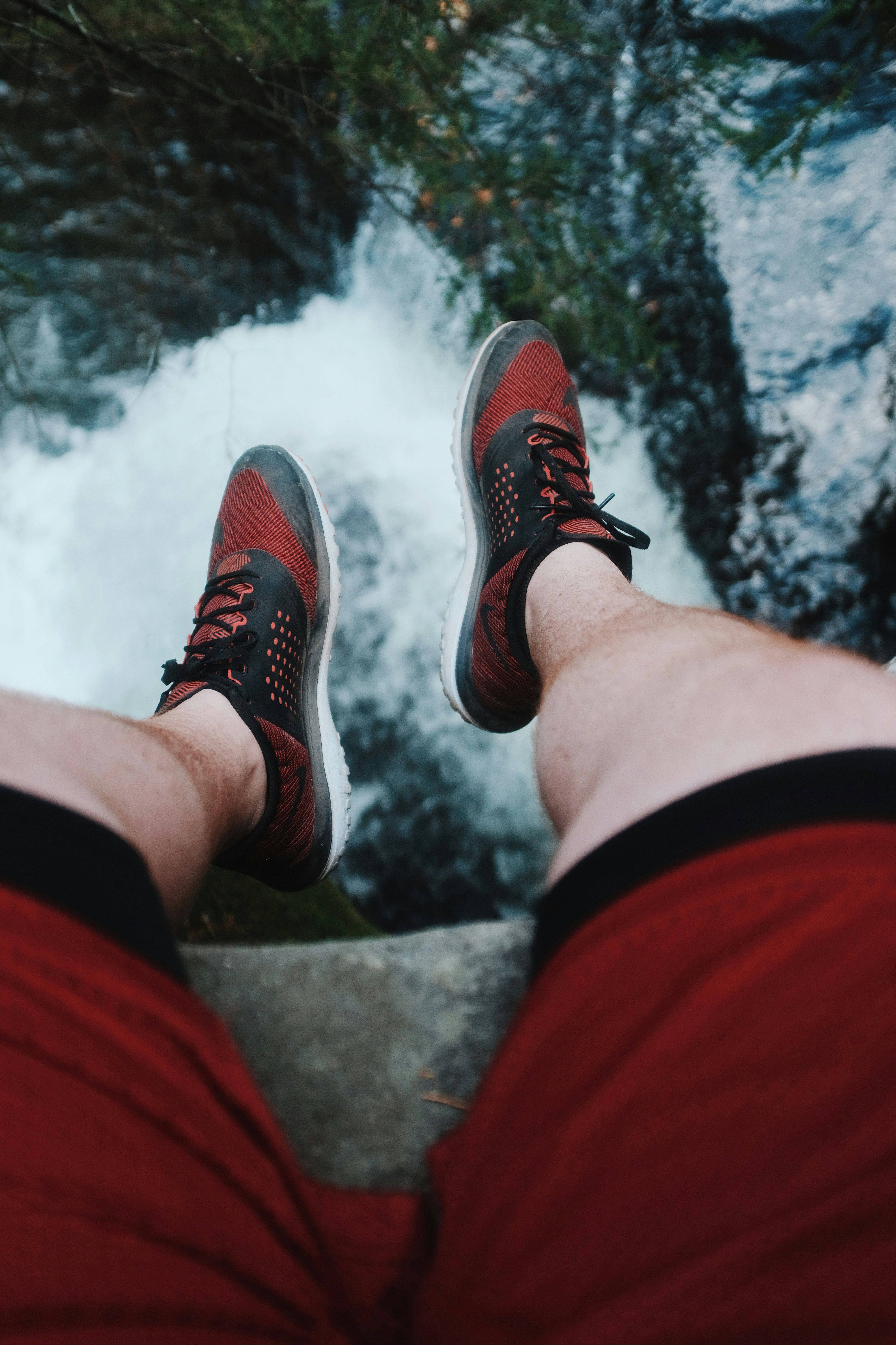 person in red shorts and wearing pair of black-and-red shoes